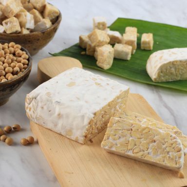 Raw Tempeh or Tempe. Tempeh Slices on Wooden Background, Cut by Asian Female Chef. Tempe Made From Fermented Soybeans. Copy Space for Text. Concept of Soy Product